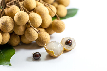 Fresh longan fruit with leaf shows the white meat with black seed isolated on white background, close up.