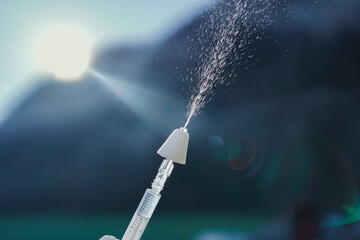 Hand using a syringe with a mucosal atomization decive (MAD) for intranasal application of drugs.