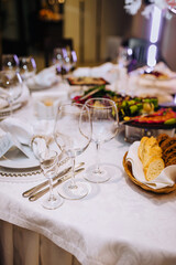 Food, glass wine glasses, knives, plates stand on a table with a tablecloth in a restaurant.