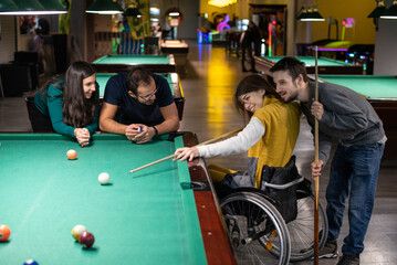 Woman in a wheelchair playing billiards with friends