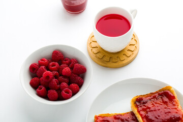 Cup of red tea and toasted bread with jam raspberry in one bowl