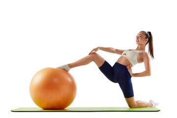 Fototapeta na wymiar Portrait of young sportive woman training, doing stretching exercises with rubber fitness ball isolated over white background. Concept of sport, fitness, health