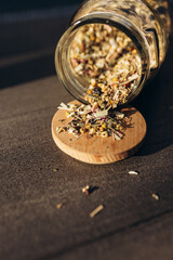 herbal tea. dried herbs. dried various herbs in next to a glass jar with rashes of herbs on a light...