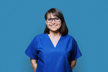 Smiling woman in blue scrubs uniform looking at camera on blue background