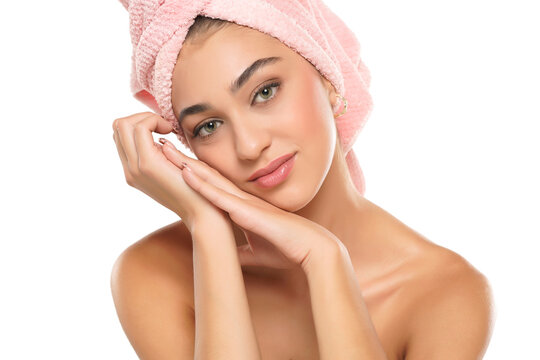 A pretty smiling young woman with towel on her head posing on a white background