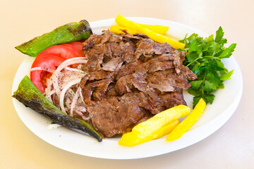 Turkish and Arabic Traditional Ramadan doner kebab with tasty tomato sauce and rice or turkish pilav in white plate on wood table background. ( Pilav ustu doner)