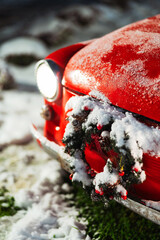 red car with christmas wreath and decorations. old red car with new year decorations and snow. Christmas car for family photo shoots on the street