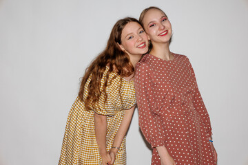 Two young cheerful women hugging on a white background.