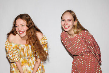 Two young women laughing merrily on a white background.