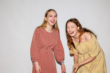 Two young women laughing merrily on a white background.
