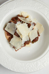 marinated fish tar tar with parmesan cheese on a white plate