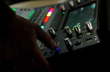 Hand of music producer while working on a mixing desk at a rock band concert