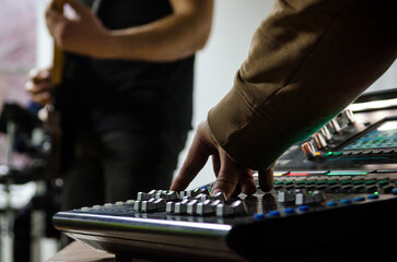 Hand of music producer while working on a mixing desk at a rock band concert