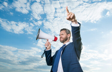 businessman shout in loudspeaker on sky background. point finger