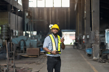 Portrait of male engineer worker working at the industry factory area. Male technician wear safety helmet and uniform working in the factory