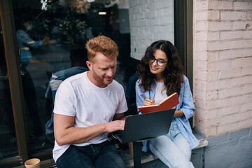 Content couple looking at screen of netbook in cafe