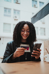 Laughing girl buying on the internet while she is sitting outdoors. She is using her credit card