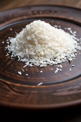 Coconut flakes separately, raw on a clay plate