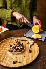 Spices for making mulled wine. The girl cuts an orange on the background