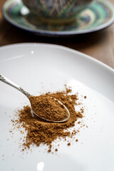 Ground cumin seeds in a spoon on a white plate