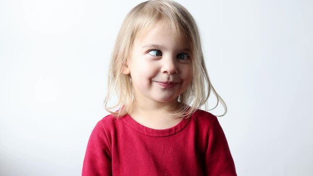 Portrait of cheerful caucasian child girl 3-4 years old showing tongue making faces at camera, fooling around, squint her eyes . Preschool little girl