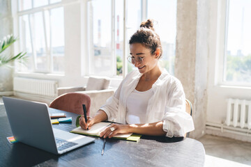 Carefree woman writing in planner at home