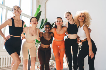 Group of diverse sportswomen standing in sunlit studio
