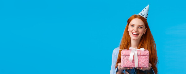 Time for present. Cheerful redhead teenage, college girl celebrating her birthday, holding cute...