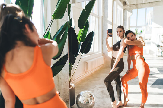 Positive women in sportswear posing for phone camera in gym - Powered by Adobe