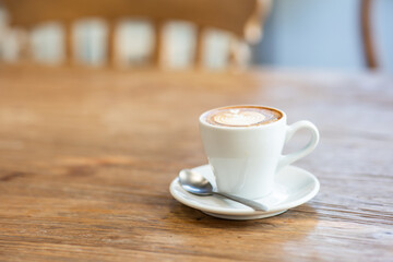 Cup of latte art or cappuccino with foam, coffee cup on table in cafe.