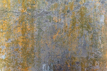 Real abstract pattern of a peeling worn wall with layers of yellow and green paints and stains of cement. Vintage old wall texture