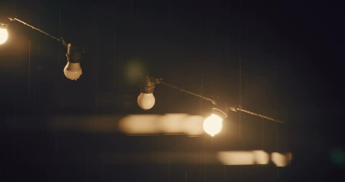 Fairy lights hanging under heavy rain with thunder storm at night static shot