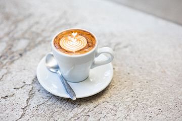 Cup of latte art or cappuccino with foam, coffee cup on table in cafe.