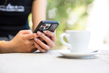 A mockup of a woman's hand holding a mobile phone in a cafe