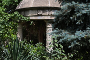 An old stone gazebo in an overgrown park