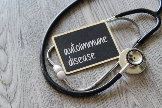 Stethoscope and chalkboard with text AUTOIMMUNE DISEASE on wooden table. Medical and healthcare concept