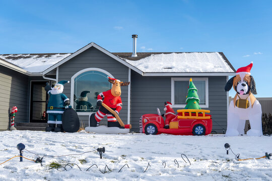 Santa Claus, car, dog, elk -inflated decorating figures on the front yard at sunny winter day. Christmas outdoor decor