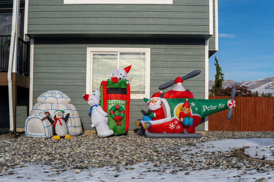 Inflated decorating figures of Santa Claus in the helicopter, penguins and bears - on the front yard at sunny winter day. Christmas outdoor decor