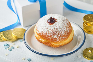 Happy Hanukkah. Hanukkah sweet doughnuts, gift boxes, white candles and chocolate coins on white wooden background. Image and concept of jewish holiday Hanukkah. Top view.