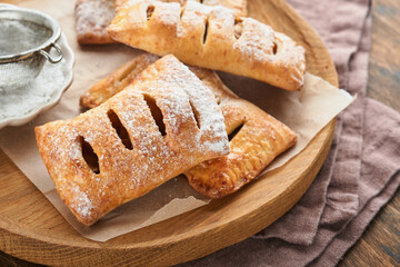 Hand pies. Mini puff pastry or hand pies stuffed with apple and sprinkle sugar powder in wooden plate. Homemade pie snack with crust for breakfast rustic photo.  Copy space.