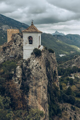Aerial view of a religious bell tower perched on rocks in a mountain landscape