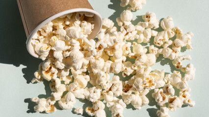 Scattered salt popcorn from craft paper cup. Concept of cinema or watching TV.