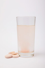 Vitamin C effervescent tablets with orange flavor drops and dissolves in a glass of water isolated on a white background. The concept of health. Medicine concept.
