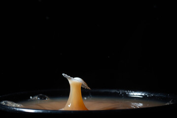 A splash of milk drops into steaming hot tea