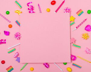 Children birthday party background with copy space paper on candels sweets cristals ribbons and confetti over pink background.