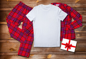 Blank white t-shirt on the background of bright pajamas on a wooden background with Christmas present