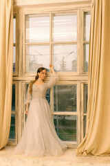 a girl in a dress by the window