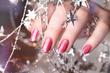 Female hand with beautiful holiday manicure - viva magenta, pink glitter nails with silver twisted...