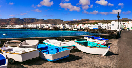 Fototapeta na wymiar Lanzarote scenic places. Charming Punta Mujeres traditional fishing village with colorful boats and white houses. popular for natural swim pools. Canary islands travel