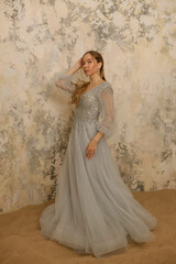 a girl in a dress on the sand against a shabby wall